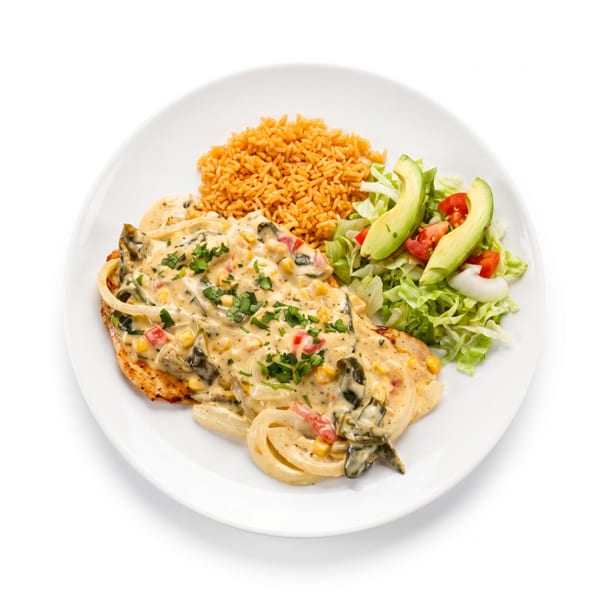 Chicken breast with creamy sauce, rice, and a side salad with avocado on a white plate.